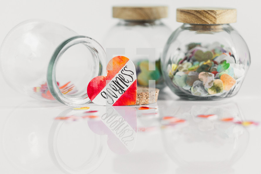 Jars of paper hearts on a white background with one lettered GOODNESS in front.