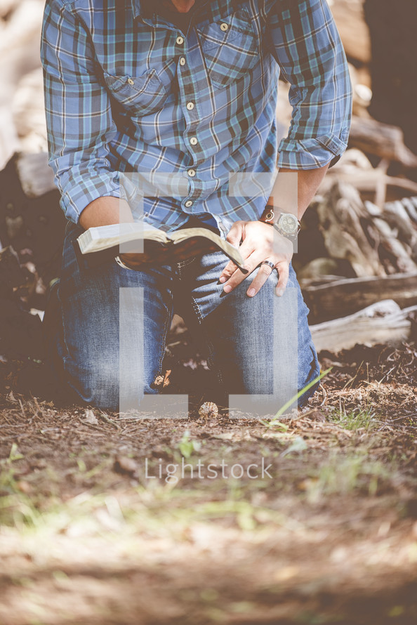 man kneeling and reading a Bible 