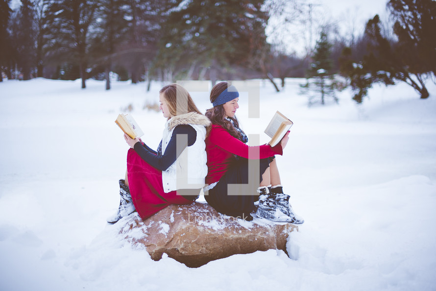 two women reading Bibles outdoors in snow 