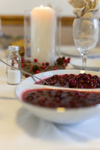 bowl of cranberry sauce on a table set for Thanksgiving 