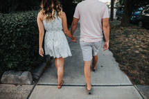 a couple walking on a sidewalk holding hands 