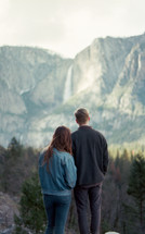 a couple taking in the view of a distant waterfall 
