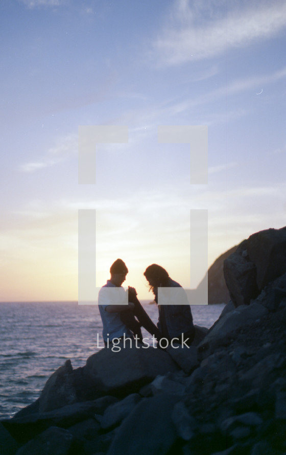 a couple exploring a rocky shoreline 