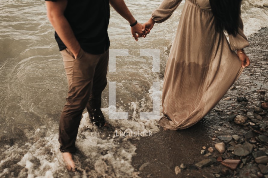 a couple standing in water holding hands 