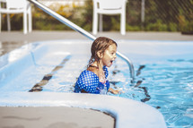 a little girl swimming in a pool 