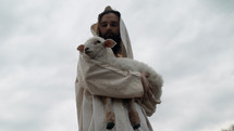 Jesus Christ as the good shepherd holding a lamb in his arms.