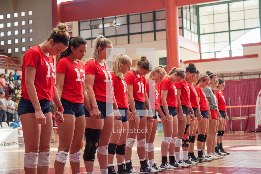 praying volleyball team holding hands 