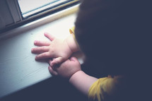 toddler hands on a window sill 