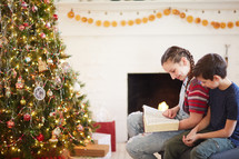 children reading the Bible around a Christmas tree