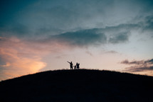 silhouette of a family standing on a hilltop 