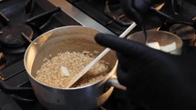 Professional Chef with gloves cooking risotto on a pot 