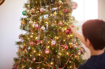 kid decorating a Christmas tree