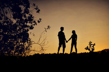 A silhouette of a couple holding hands.