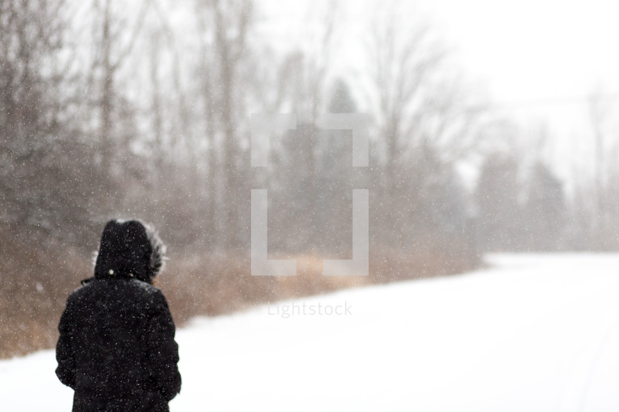 a person in a coat walking outdoors in snow 