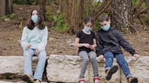 Coronavirus pandemic - kids wearing face masks to avoid contagion sitting bored