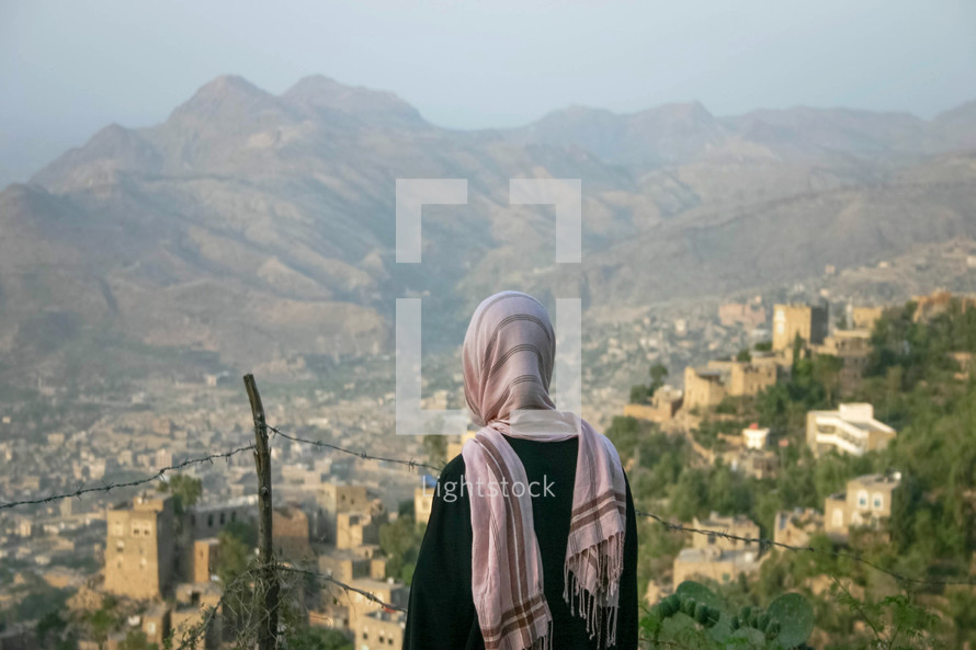 a shrouded woman looking out at a city in Yemen 