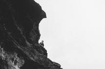 Woman taking a photo with her i[hone at the top of a cliff.