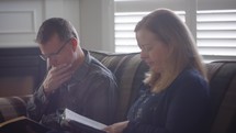 a husband and wife reading a Bible together 