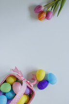 plastic Easter eggs in a basket and tulips