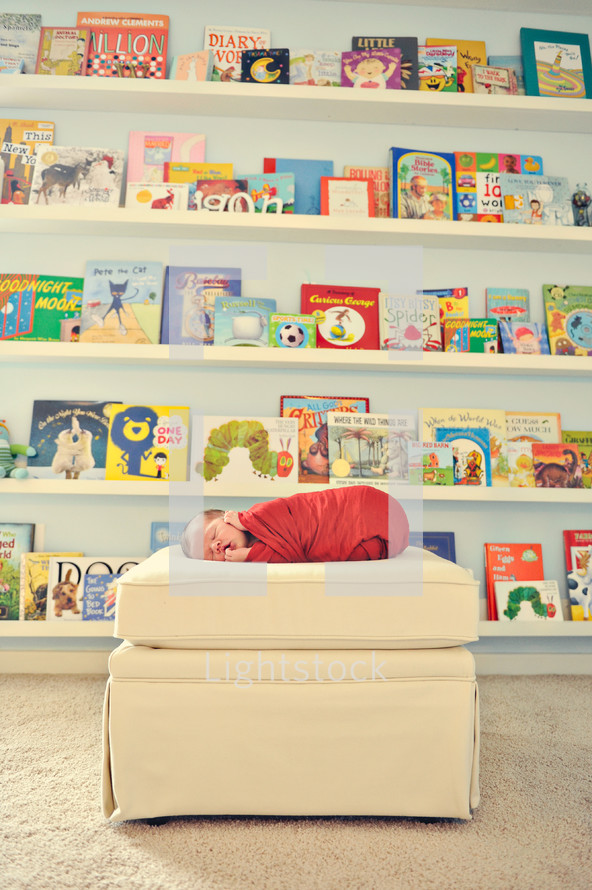 children's books and a newborn on an ottoman 
