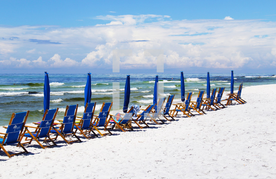beach chairs and umbrellas on a white sand beach 