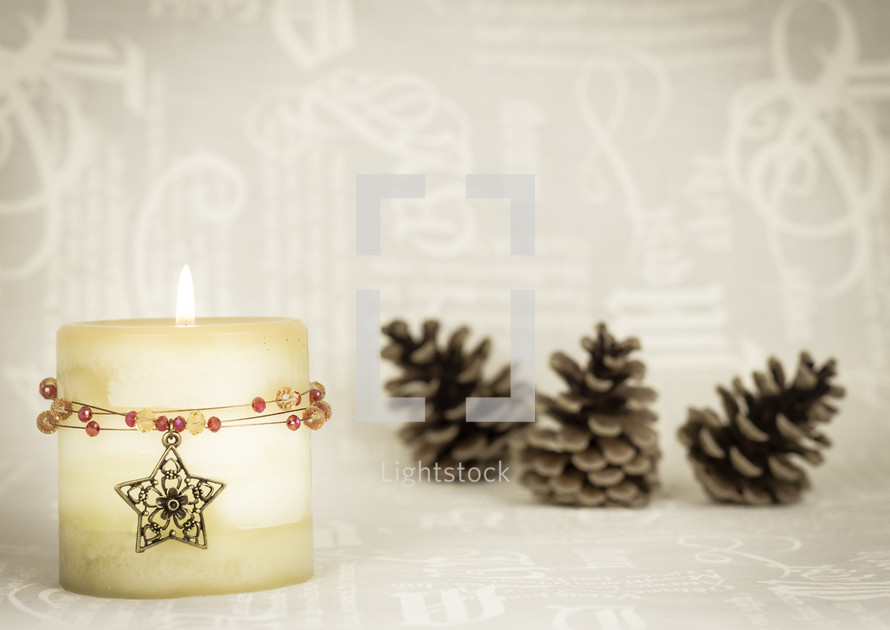 Christmas candle with star and jewels, cream text background, pinecones