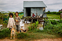 children, dog, and hut in swampy water 