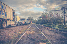 dump truck and trucks parked by old train tracks 