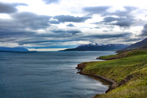 snow capped mountains and green shoreline 