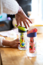 Mom filling sippy cups for children 