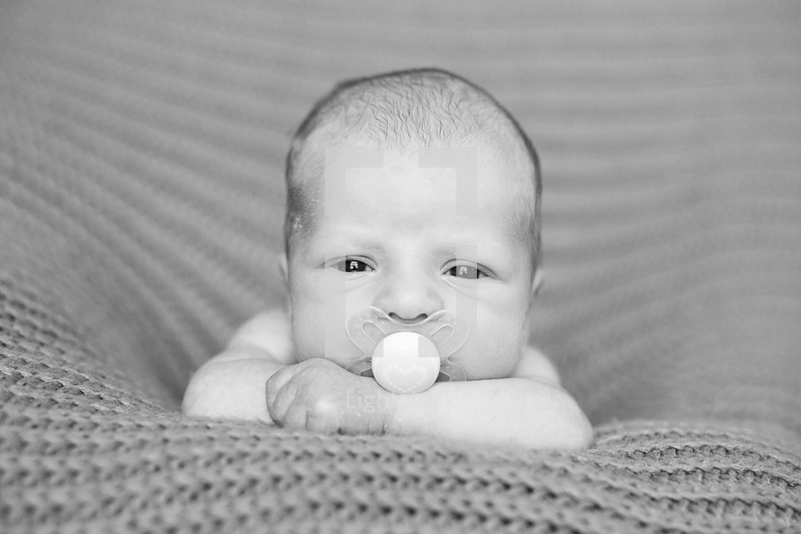 newborn baby with a pacifier in his mouth 