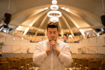 a man in prayer in an empty church 