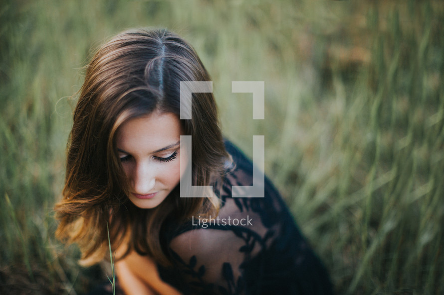 teen girl crouching in a field 