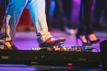 a man on stage with his foot on a guitar pedal 