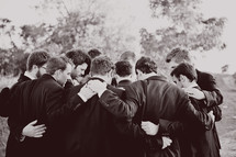 men in suits in a group prayer