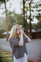 A blonde woman taking a picture with a camera.