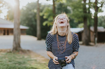 A laughing young woman holding a camera.