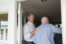 Man greeting father as he walks into his house. 