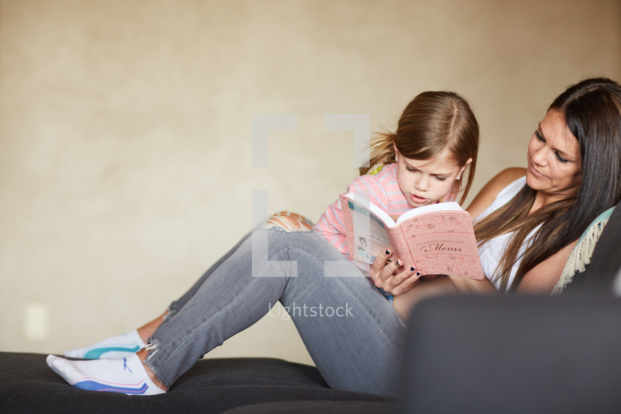 a little girl reading a book to her mom 