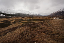 plains in a valley and snow capped mountains 