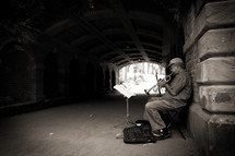 street musician playing a trumpet under a tunnel