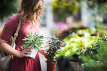 a woman picking out plants in a garden center 
