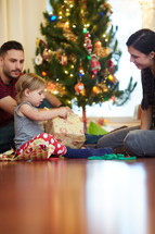 a mother and father giving her daughter a present to open at Christmas 