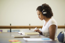 a woman reading a book and listening to headphones 