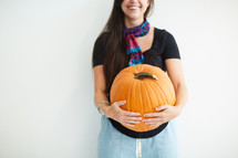 a woman holding a large pumpkin 