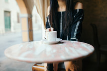 woman sitting at a table alone with a coffee mug 