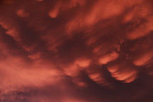 Dramatic sunset landscape with puffy clouds lit by orange setting sun and blue sky