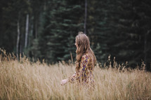a girl walking through field in autumn