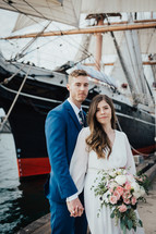 bride and groom standing in front of a ship 