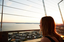 a woman looking over a balcony at coastal town below 